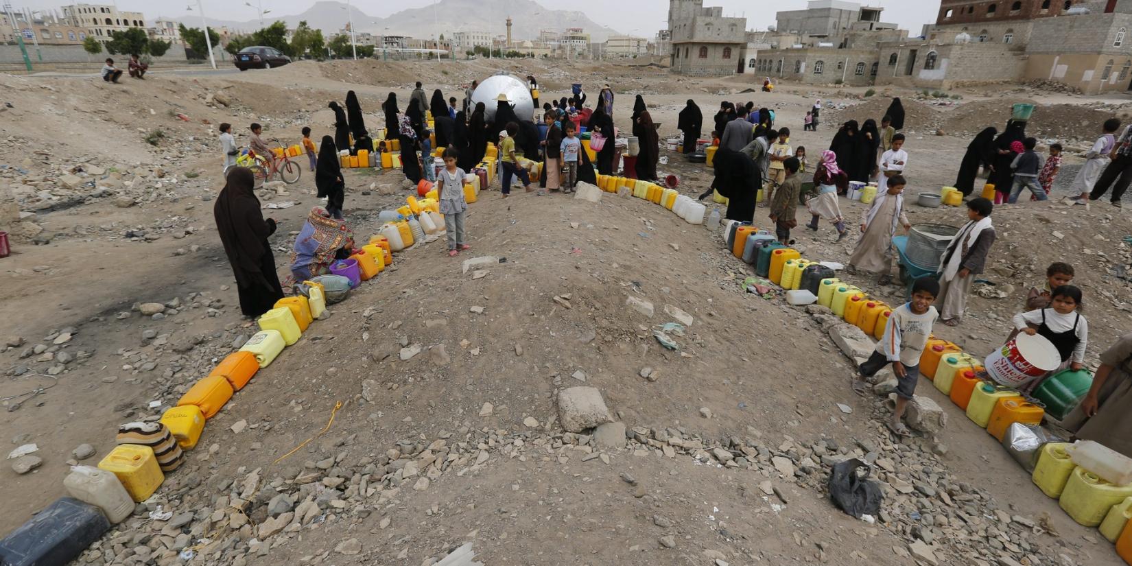 Yemeni women and children wait to fill jerry cans with water from a spring. © Keystone