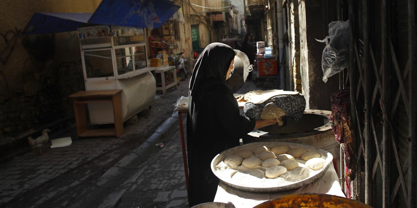 A woman bakes bread in the streets of Baghdad.