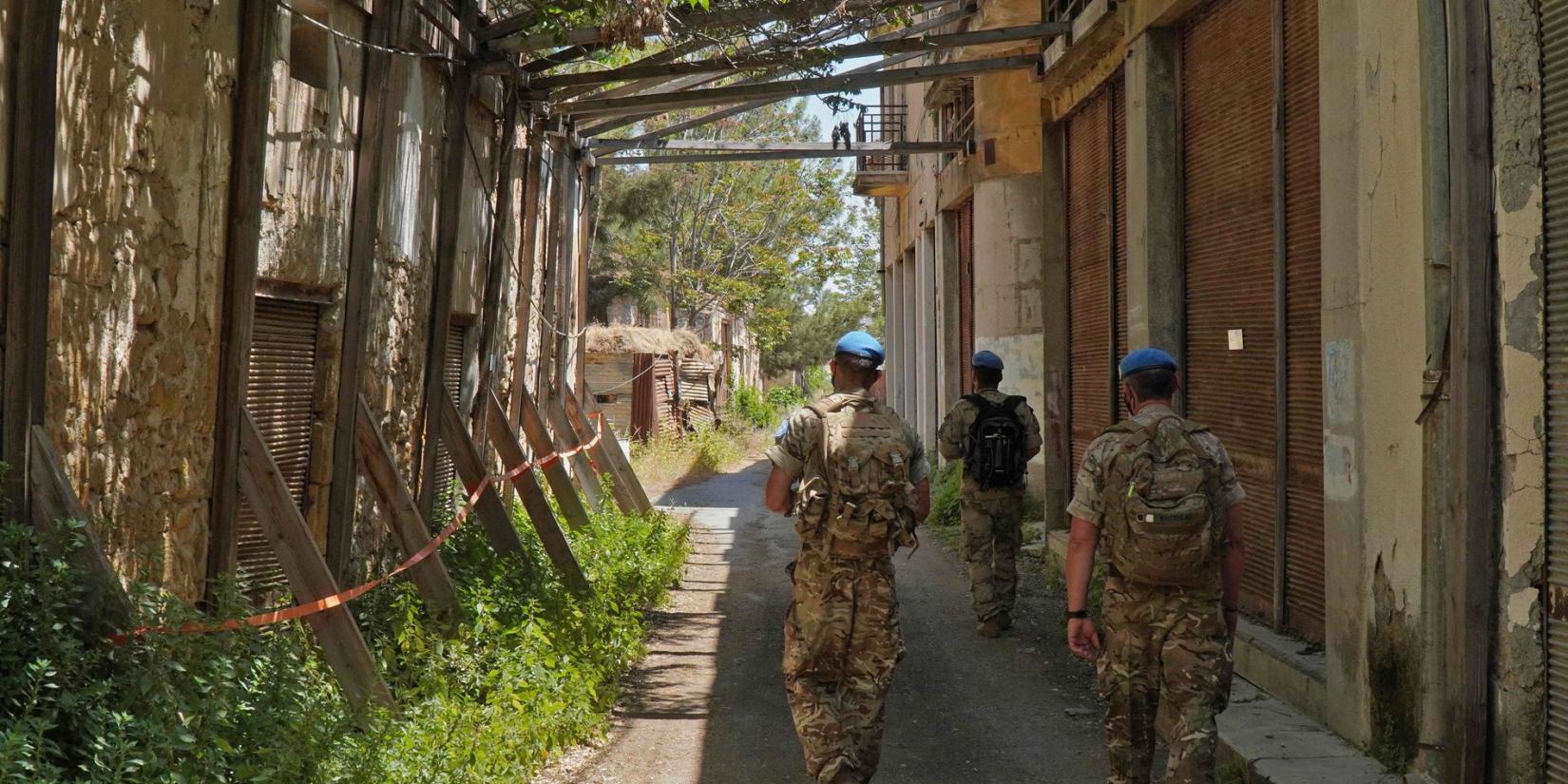 Members of the UN peacekeeping force UNFICYP walk through an alley between dilapidated buildings in the buffer zone.