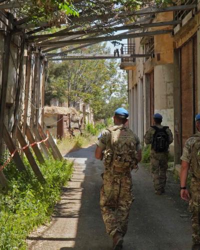 Members of the UN peacekeeping force UNFICYP walk through an alley between dilapidated buildings in the buffer zone.